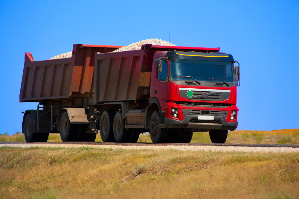 Red dump truck with the trailer loaded with rubble on a road near North Kansas City, MO