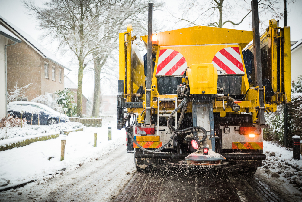 Winter service truck spreading salt and sand on the road surface to prevent icing in Leawood, KS.