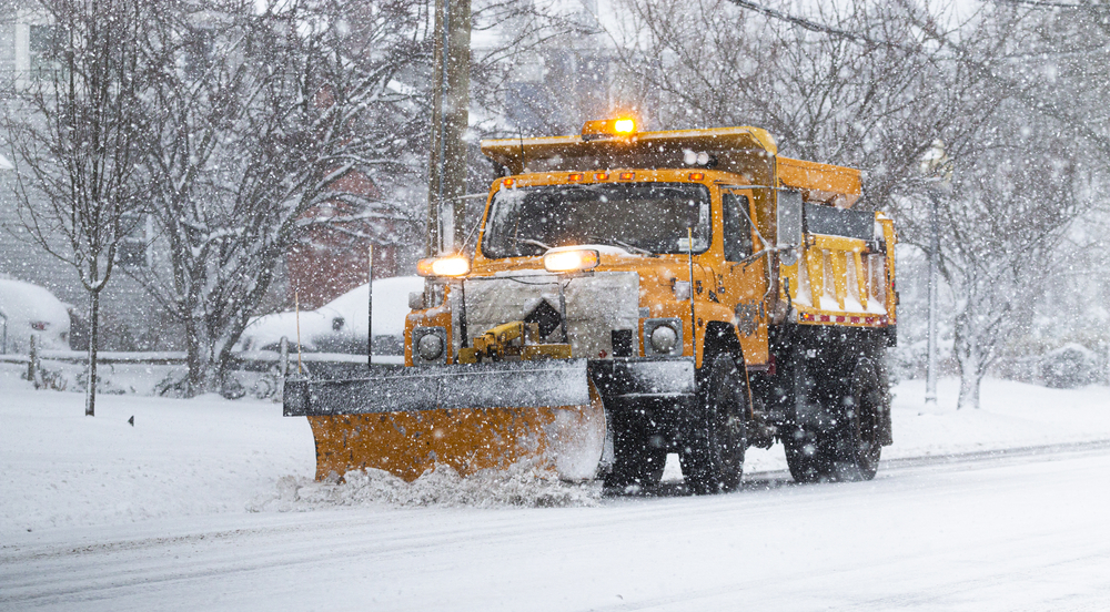 A towns yellow snowplow trying to clear the roads with heavy snowfall making it very difficult in Leawood, KS.